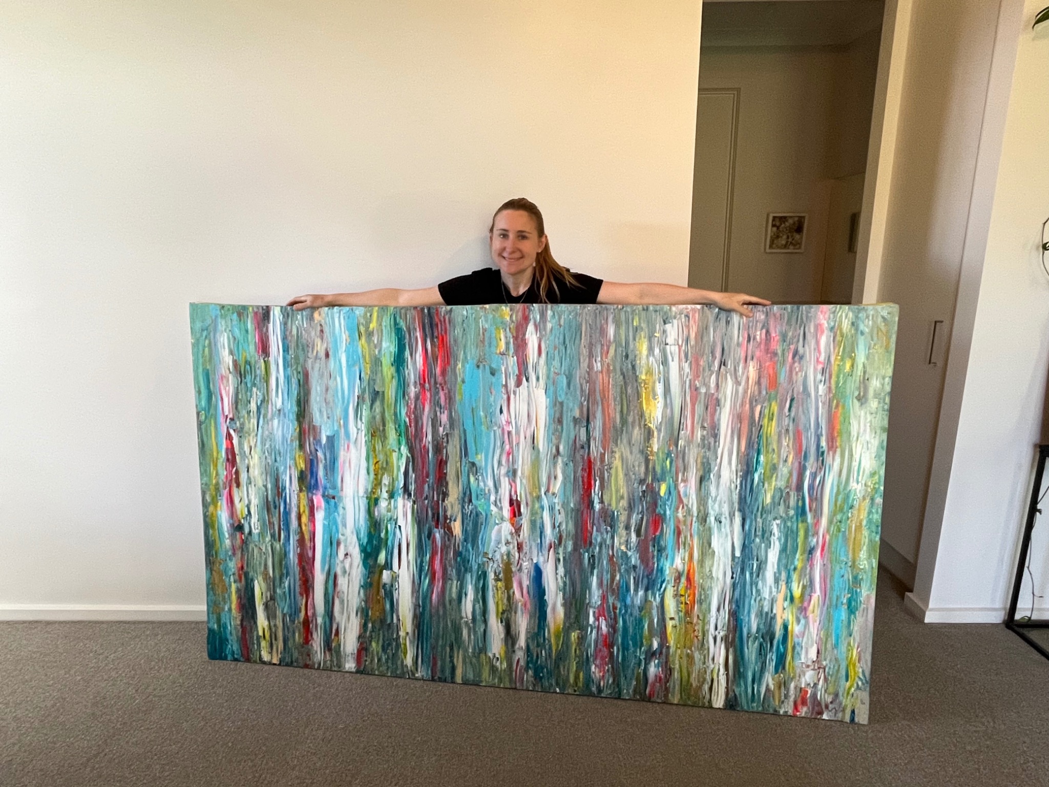 Tink holding a large colourful abstract painting